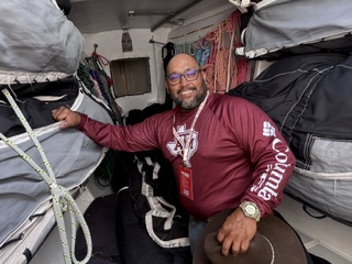 Jay Molina below decks among the stowed sail bags during an offshore passage